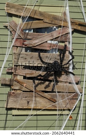 Large Fake Spider and Web on Boarded Window of House