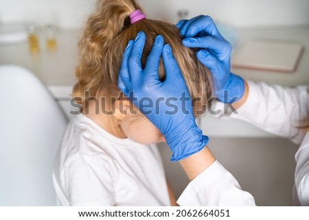little girl at the reception of a dermatologist on examination of hair for lice, pediculosis