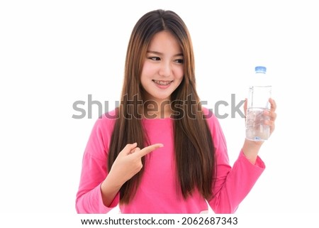 Happy young Asian woman showing a bottle of water,thirsty every day or fill energy after exercise playing sport workout,concept positive emotions and facial expression,isolated on white