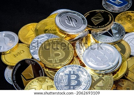Horizontal view of cryptocurrency tokens, including Bitcoin, Ethererum Ripple, and Litecoin saw from above on a yellow gold background. High quality photo