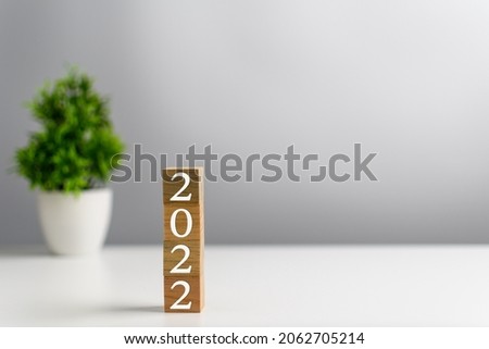 New year 2022 wood cube is on a work table. Concept of a startup that drives the economy, finance, banking, forward, future, glowing, startup, strategy, success. Copy space, Blurred, grey background