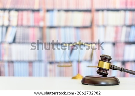 Legal office of lawyers, justice and law concept : Judge gavel or a hammer and a base used by a judge person on a desk in a courtroom with blurred weight scale of justice, bookshelf background behind Royalty-Free Stock Photo #2062732982