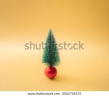 Christmas tree on a red bauble. Minimal concept and design. Yellow gold background.