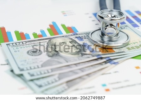 Finance and economics concept. Coins and a stethoscope are on the documents with graphs and diagrams.