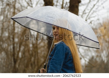 young girl with umbrella walking in at beautifu autumn park. modern girl in casual clothes walks through the city park. Seasonal style, autumn beauty. autumn season, in a blue jacket, in autumn leaves
