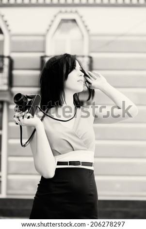 beautiful young woman taking photos with vintage camera on a city street