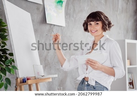 Photo portrait young girl wearing white shirt keeping brush creating painting on canvas staying at home
