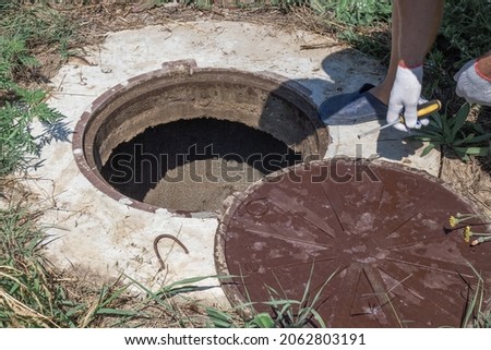 The man opened the manhole cover of the well. Checking and installing water metering. Royalty-Free Stock Photo #2062803191