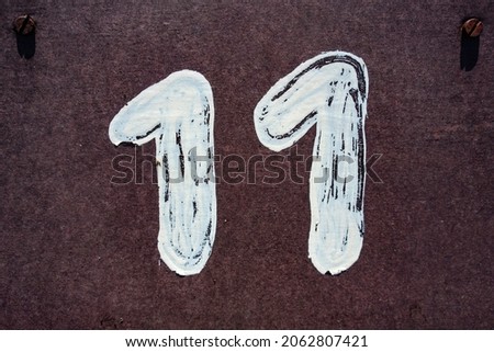 Hand painted house number eleven (11) on concrete plywood Royalty-Free Stock Photo #2062807421