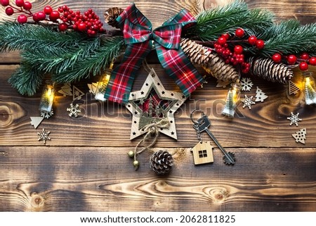 House key with keychain cottage on a festive eco friendly, natural background with Christmas tree. Happy New Year, gift, greeting card. Purchase, construction, relocation, mortgage