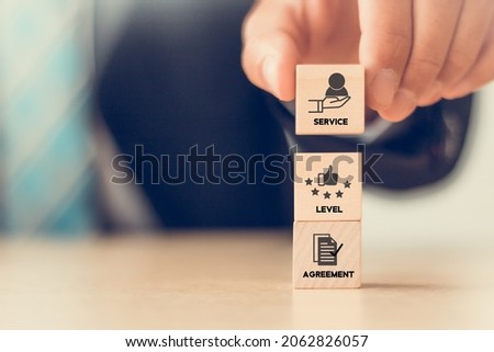SLA - Service Level Agreement acronym, business concept. Service performance tracking to reduce the uncertainty the customer in process. Hand holds  wooden cubes with Service Level Agreement symbols. Royalty-Free Stock Photo #2062826057