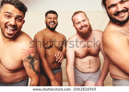Having fun while shirtless. Three happy men smiling at the camera while wearing underwear in a studio. Body positive and self-confident men celebrating their natural bodies. Royalty-Free Stock Photo #2062826969
