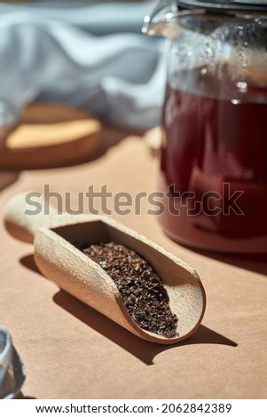 Brewed tea in a glass teapot on a brown background. Turkish tea in a wooden spoon