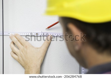Construction worker drawing straight line using folding ruler