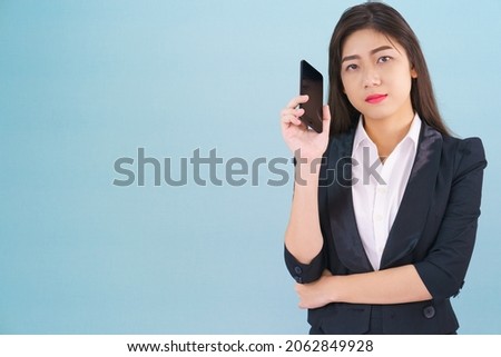 Young women in suit holding her phone standing against blue background