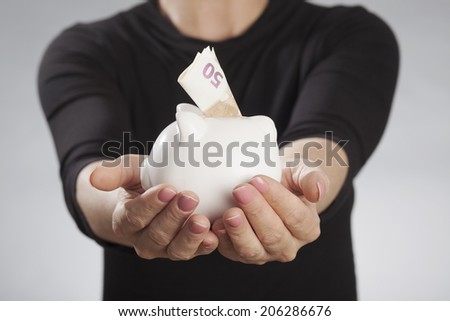Woman holding piggy bank against gray background