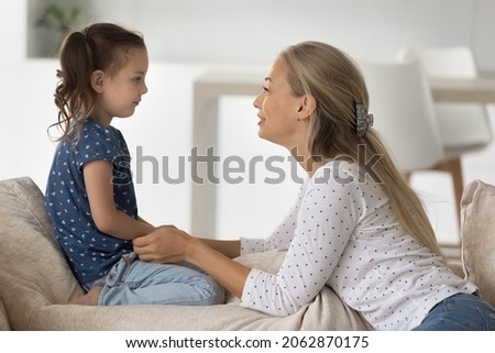 Side view smiling young woman holding hands of little cute kid daughter, involved in sincere conversation at home, helping solving problems or giving advices, trustful family relations concept. Royalty-Free Stock Photo #2062870175