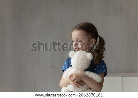 Happy adorable little preschool kid girl cuddling favorite fluffy teddy bear, copy space for advertising toys for children. Thoughtful stressed small child feeling lonely indoors, adoption concept. Royalty-Free Stock Photo #2062870181