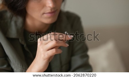 Depressed sad young woman taking off and holding wedding ring. New widow feeling emotional pain, grieving after loss. Divorcee going through depression, apathy, heartbreak crisis. Close up Royalty-Free Stock Photo #2062870220