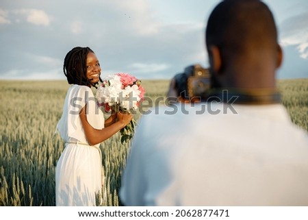 Happy couple with camera at summer field