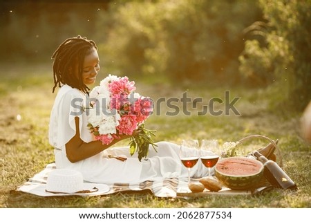 Black woman with peonies on a blanket