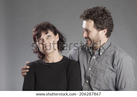 Mature couple embracing man smiling woman doubting
