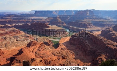 Dramatic desert view overlooking river winding through red canyon landscape on a hot summer evening. Taken at Dead Horse Point State Park, overlooking Colorado River and Canyonlands, Utah. Royalty-Free Stock Photo #2062886189