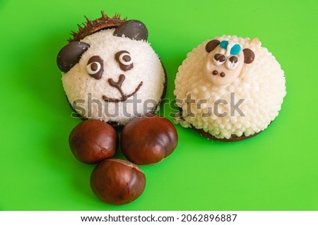 A cake with the image of a panda and a sheep for children on a green background with nuts. Curly cake for children. Marshmallows with cookies in the form of animals. Natural sweet dessert.