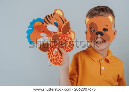 Child in a bear mask holds a set in his hand. Set of assorted animal masks, DIY toys, dress up costumes mask, party supplies, birthday party favors, play accessories, photo booth props for kids