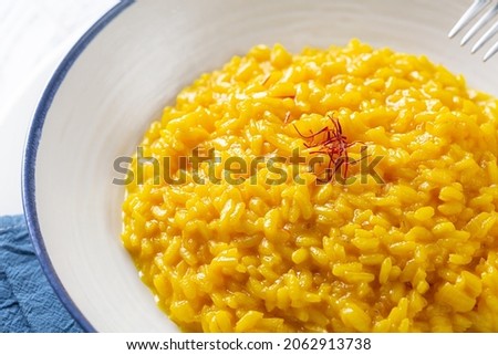 Risotto allo Zafferano. Italian dish made from saffron, rice and vegetable bouillon. Close-up. Royalty-Free Stock Photo #2062913738