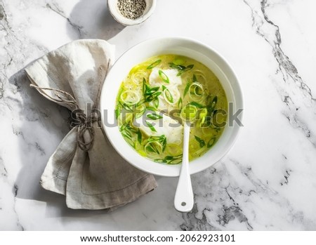 Cod, leek and rice broth on a light marble background, top view. Delicious diet soup for lunch   