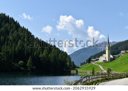 Lago di Valdurna in Alto Adige, clear skies and reflections on the surface, typical church with pointed bell tower