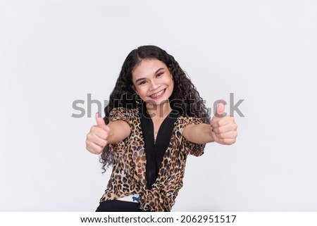 A happy and supportive young woman gives a double thumbs up. Wearing a leopard print tie waist blazer. On a white background.