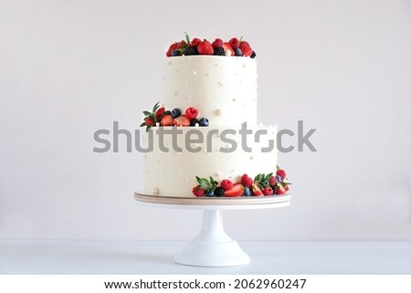 White wedding cake, with slices strawberries, raspberries, blackberry on a white background. Royalty-Free Stock Photo #2062960247
