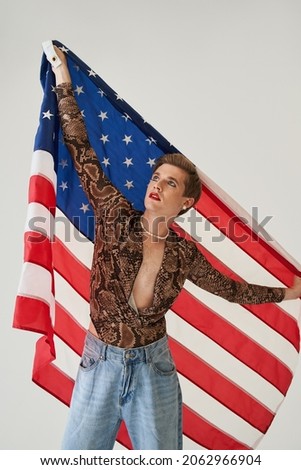 Caucasian bisexual man holding united states flag in his hands
