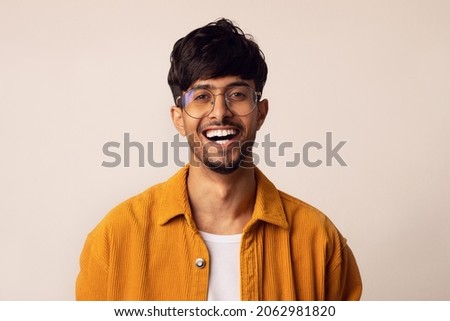 Closeup portrait of happy bearded arabic guy wearing glasses laughing at camera over grey studio background, copy space. Handsome middle-eastern young man in casual showing positive emotions Royalty-Free Stock Photo #2062981820