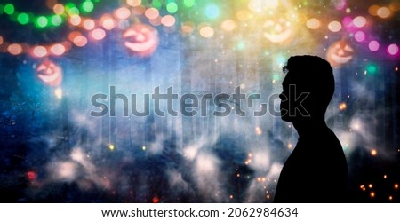 Back silhouette of unrecognizable man isolated on magical background for Halloween with garlands, bokeh lights,hanging glowing pumpkins, smoke.Mystical night forest with jack o lantern.Copy space 