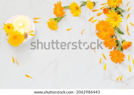 orange marigold  flowers with burning candles   on white marble background