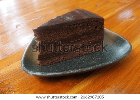  Delicious slice of tasty homemade chocolate cake on wood table. 