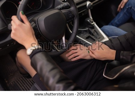 woman's hands holding on to the wheel of a new car in the showroom.