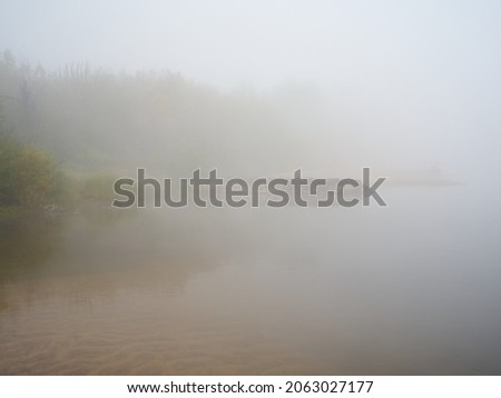 Dense fog on the river in the early morning. Autumn.