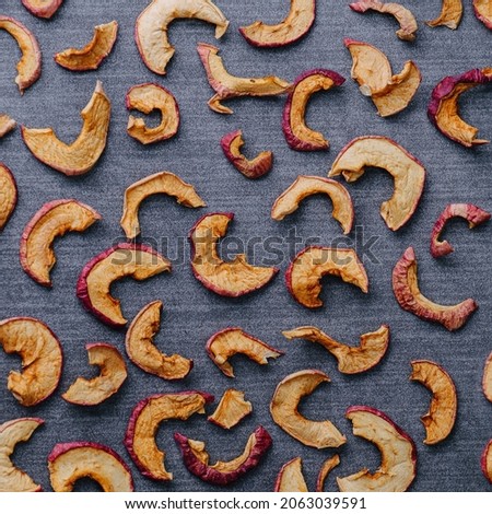 Multitude of dried apple slices on a grey textile surface. Pattern. Texture. Top view, flat lay.