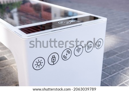 Bench with solar battery to power wifi and charge mobile devices. Alternative sources of energy. Environment concept. Royalty-Free Stock Photo #2063039789