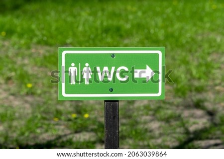 WC logo, sign of public toilets on the street against grass background. 