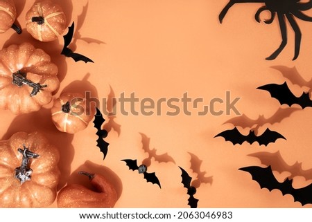 Halloween holiday concept. Pattern from paper bats of pumpkins and decor. Flat lay on orange background with copy space
