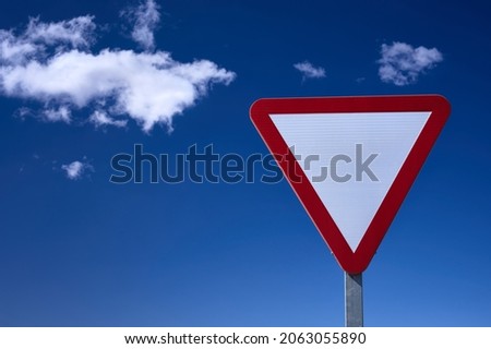 detail of a give way traffic sign over a blue and cloudy sky