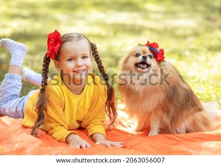 A girl with a Spitz dog, a small child is resting in the park with her pet, taking care of pets, a dog is a friend of man.
