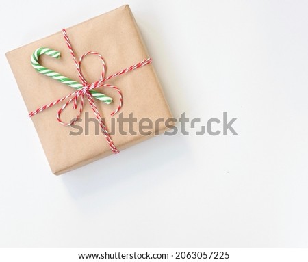 A Christmas gift wrapped in craft paper is decorated with a lollipop.