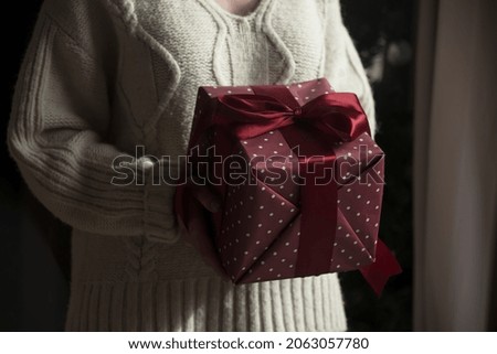 Woman in sweater holds gift box at home