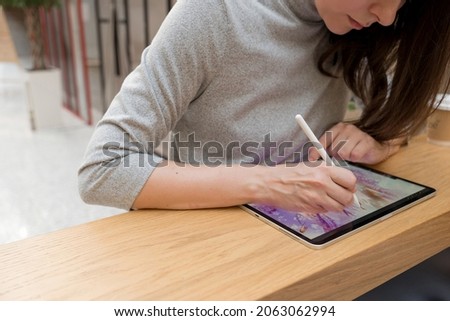 A digital artist draws on a graphic screen tablet, modern technologies for creativity. A young woman artist or designer uses a tablet to draw
